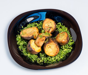 Roasted potato on black plate on white background