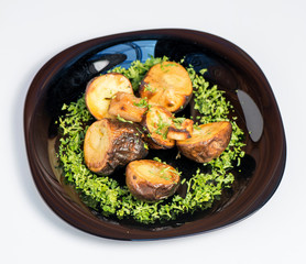 Roasted potato on black plate on white background