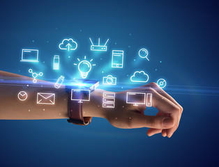 Close up female hand with smartwatch and multimedia symbols around and blue background
