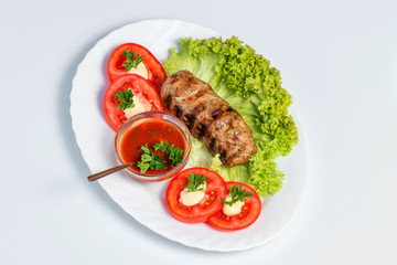 Meat grilled. Meat filed on a white plate with lettuce leaves and tomatoes