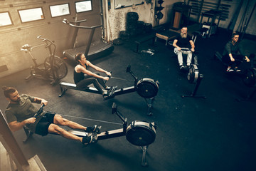 Fit people using rowing machines during an exercise class
