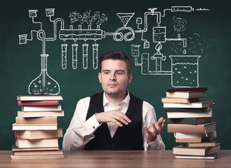 A young chemistry teacher in the middle of a chemical process explanation with tubes, reactions drawn on the blackboard back to school concept.