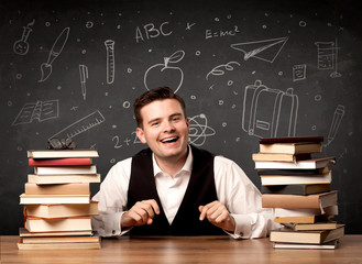 A passionate young teacher sitting at school desk with pile of books in front of blackboard drawn full of back to school items concept.