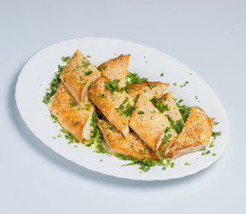 A puff pastry pie with cheese coated with sesame seeds