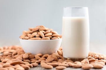 Milk and Pile of almonds nut in a while bowl against wooden background select focus shallow depth of field