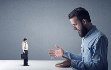 Young professional businessman being angry with an other miniature businessman 