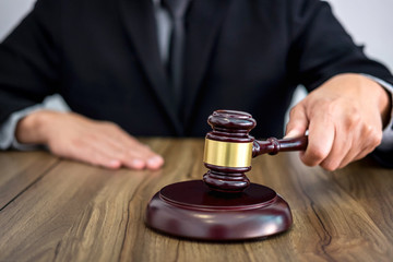 Male lawyer or judge hand's striking the gavel on sounding block, working at courtroom, Law and justice concept