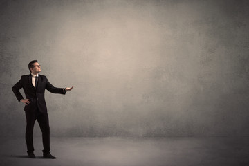 Caucasian businessman standing in front of a grunge, blank wall