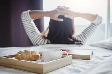Relaxation and recreation, Young happiness woman on the bed with old book and morning cup of coffee and Croissant
