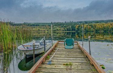 Shelton, Washington State, USA - October 7, 2015: Jetty on a lake with small boat in an autumnal sunset