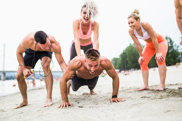 Group of young attractive people having fun at beach and doing some fitness workout. 