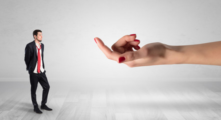 Businessman with kisses on his face in an empty space where a big hand baiting him

