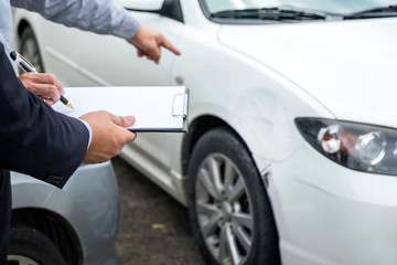 Insurance Agent examine Damaged Car and filing Report Claim Form after accident, Traffic Accident and insurance concept