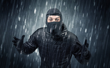 Burglar in action in black clothes with rainy concept. 