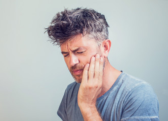 Man holds his hand near the cheek toothache