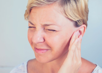 young female having ear pain touching her painful head earache