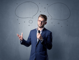 Businessman speaking into microphone with speech bubbles over his head