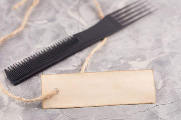 Single new black plastic comb and old blank rectangle paper with hole and long rope on cracked gray cement