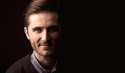 young man close up portrait, on black background