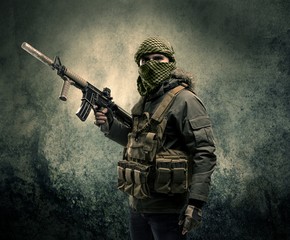 Fototapeta premium Portrait of a heavily armed masked soldier with grungy background concept