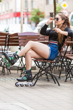 Young woman sitting wearing roller skates