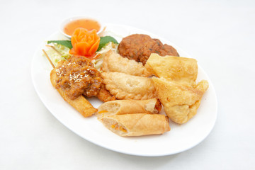 Mixture of Thai appertizers with deep-fried spring rolls, curry puffs, wontons, fish cakes and chicken satay skewers