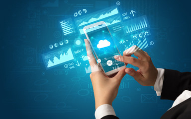 Obraz premium Female hand using smartphone with financial tracking concept illustrated by graphs and symbols