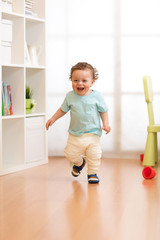 First steps of baby toddler learning to walk in living room. Footwear for little children.