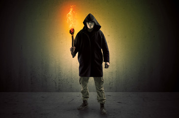 Ugly scary man with burning flambeau walking in an empty space