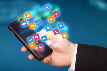 Hand using phone with colorful fast moving application icons and symbols concept
