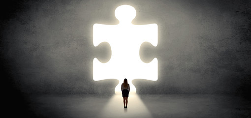 Woman standing and looking to a big puzzle piece
