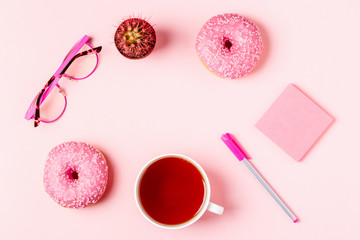 Cup of tea with donuts on a pink pastel background