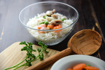 Chicken fricassee with green pea served with boiled rice on a wooden background.