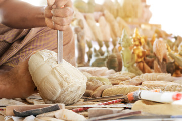 Naklejka premium Craftsman using a tool on a sandstone to carve a statue