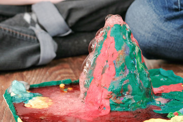 Mom and son's hands make experience with plasticine volcano at home. Chemical reaction with gas...