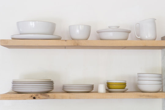 Various ceramic crockery arranged on wooden shelf