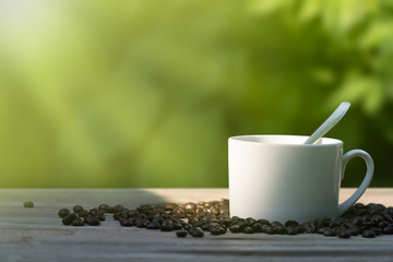 Coffee cup and coffee beans on vintage wooden table top in morning sunlight
