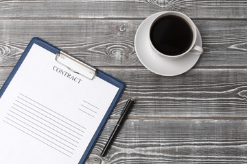 a cup of coffee, a contract form, a pen for writing on a wooden background. finance. contract signing