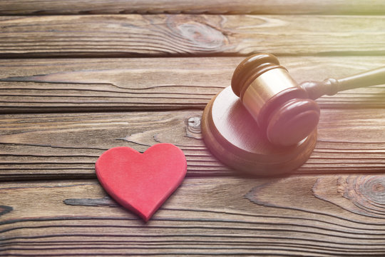 a wooden red heart figure, a judge hammer on a wooden background. family law.
