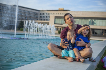 Fototapeta na wymiar Father with two kids by the fountain
