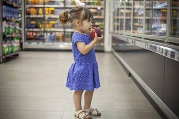 Little girl eating apple in the supermarket