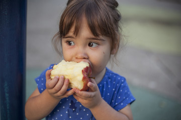 Little girl eating apple at the playground