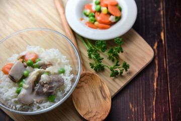 Chicken fricassee with green pea served with boiled rice on a wooden background.