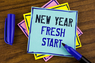 Handwriting text writing New Year Fresh Start. Concept meaning Time to follow resolutions reach out dream job written on Sticky note paper on wooden background Marker next to it.
