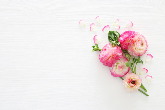Image of delicate pastel pink beautiful flowers arrangement over white wooden background. Flat lay, top view.