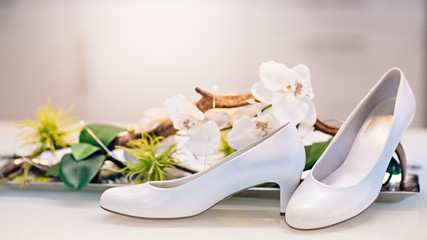 White bride shoes near a vase with white orchids