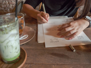 Fototapeta na wymiar hands young female sketching drawing or writing in coffee shop on wooden table with greentea and tea on vintage look