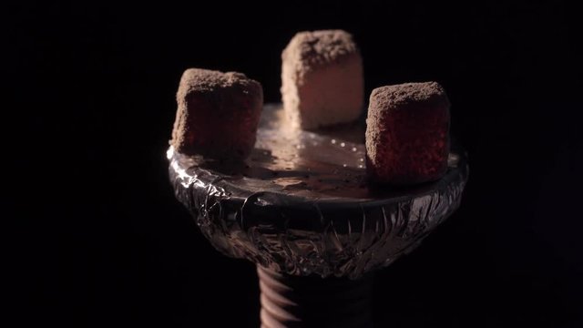 Hookah bowl with coals and smoke on black background