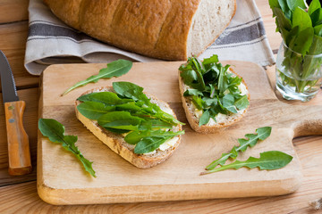 Two slices of sourdough bread with butter and dandelion leaves