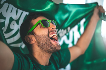 Naklejka premium Saudi Arabia fan celebrating with flag